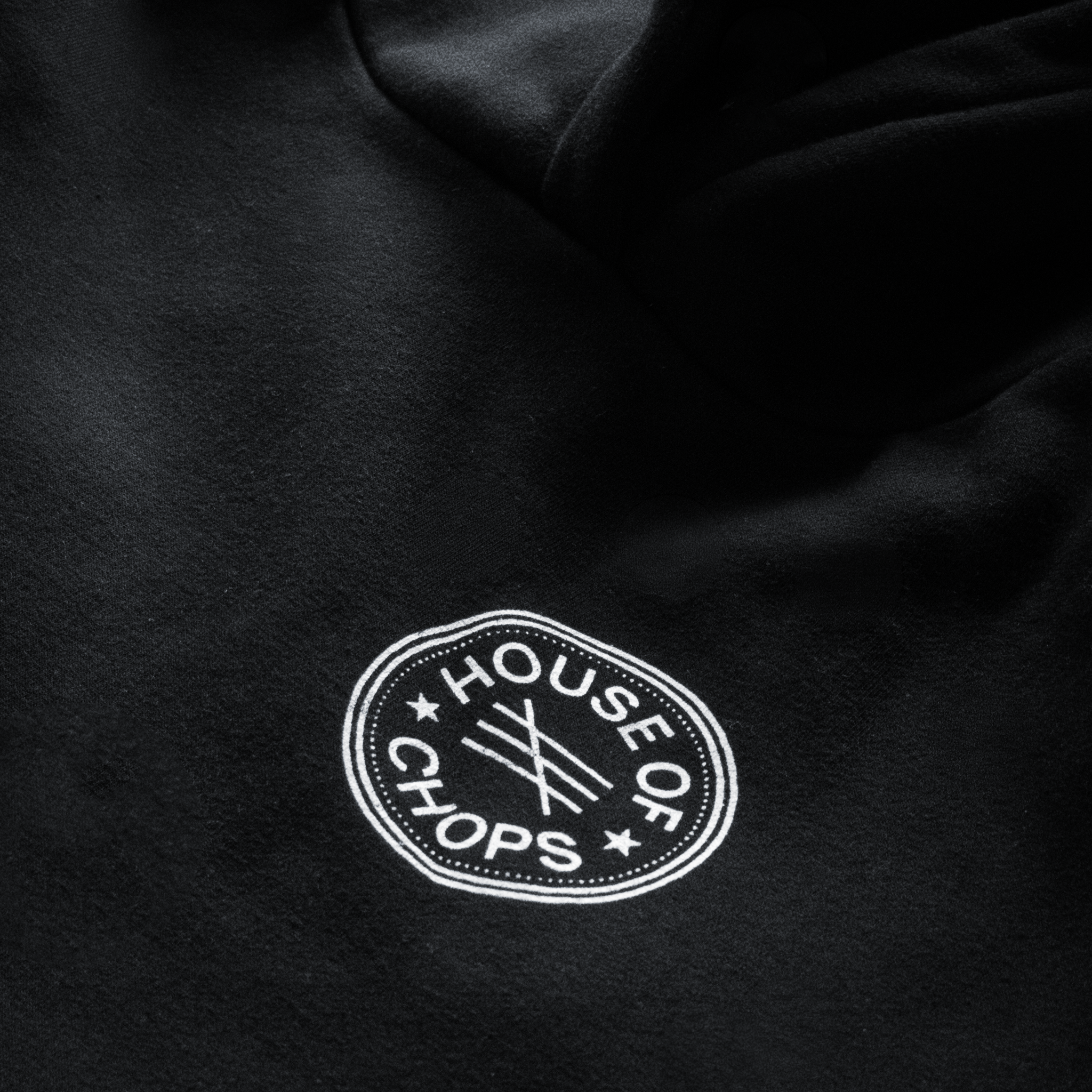 Detail shot of print quality on Cut 001 black hoodie showing fabric texture and design clarity.