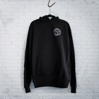Cut 001 black hoodie front displayed on hanger showing natural drape and heavyweight fabric construction - against a white wall.